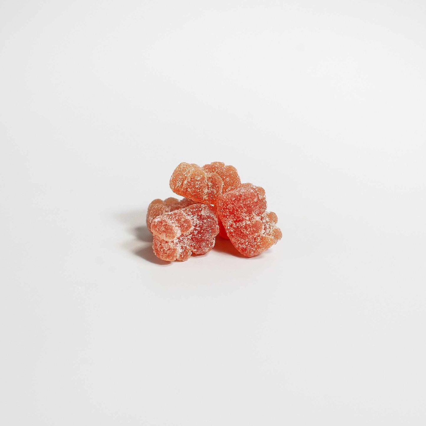 Three red sugar-coated multivitamin bear gummies for adults on a white background